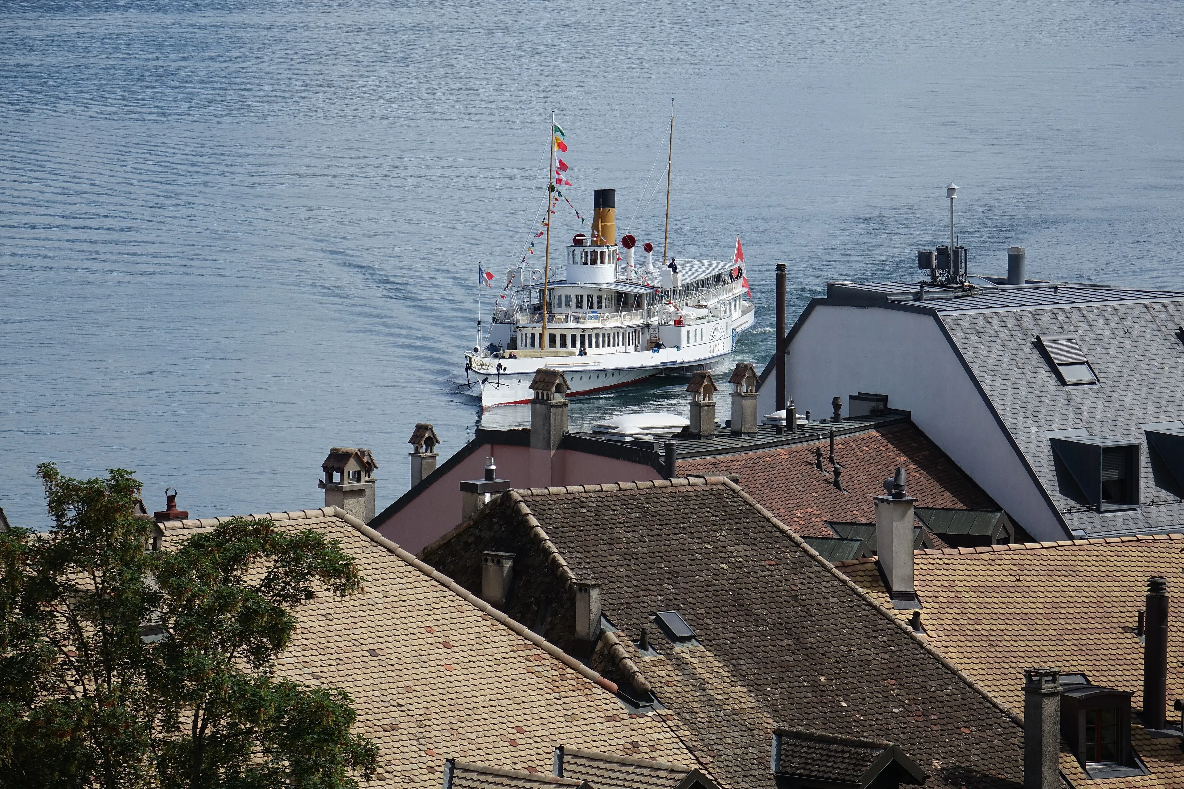 Toits d'une localité vaudoise au bord du lac Léman et bateau à vapeur historique de la CGN, canton de Vaud.
